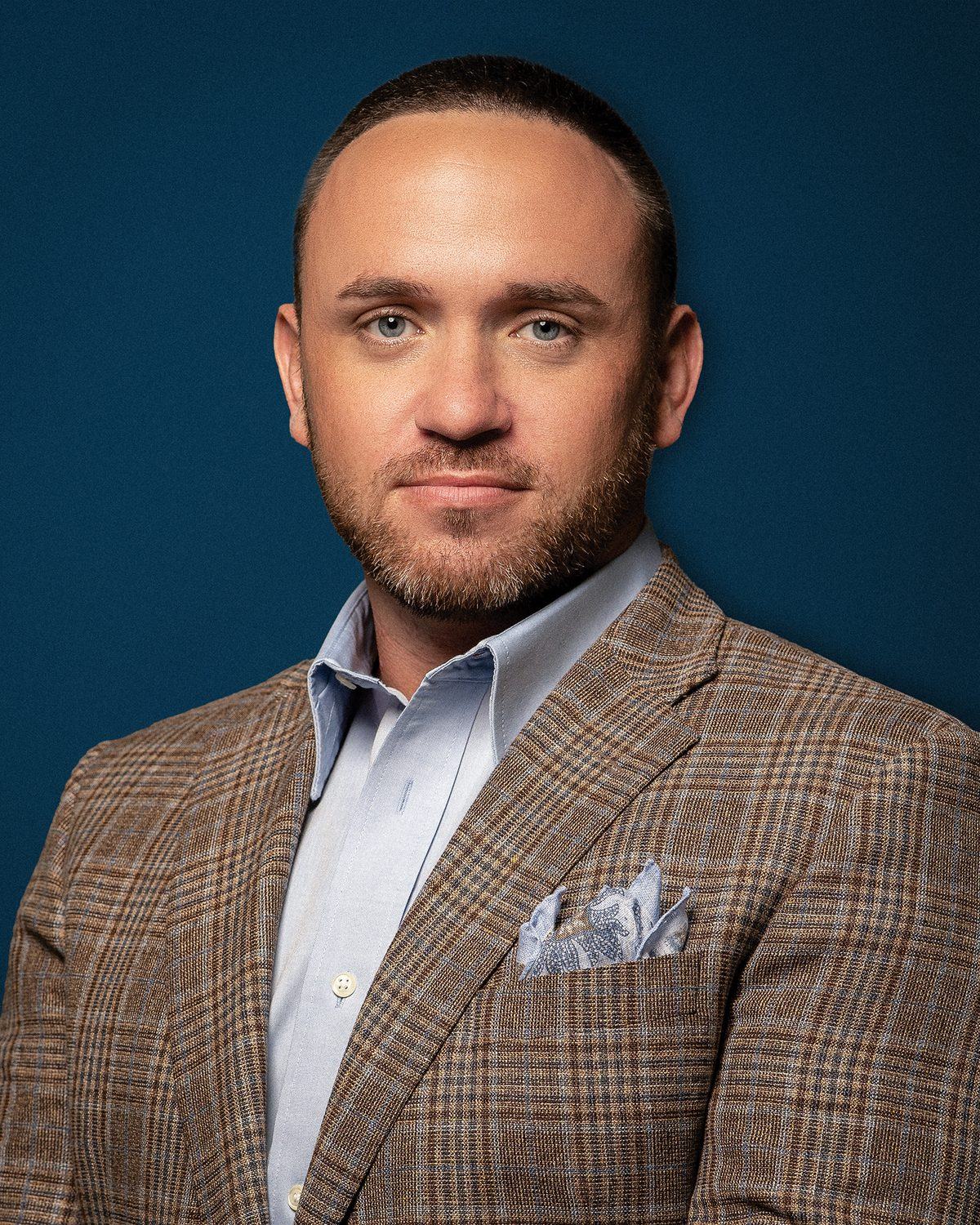 Justin Stark, studio portrait in a plaid blazer